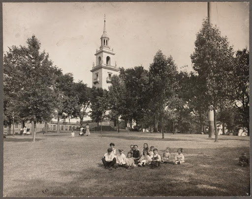 A group of children sit on the grass in front of Dorchester Heights Monument circa 1902-1920