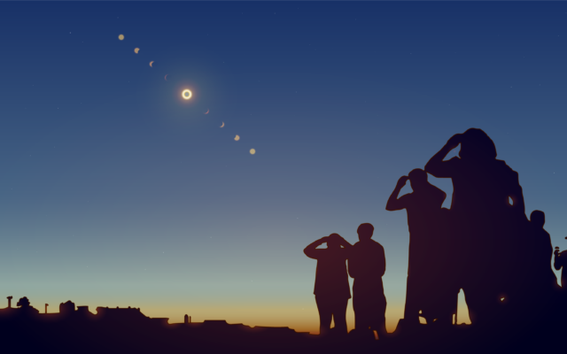 Silhouette of people against a dark blue sky, looking up at the eclipse.