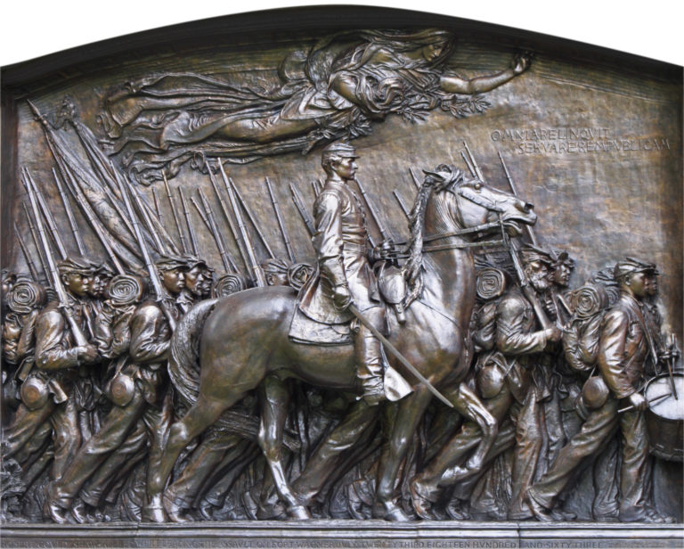 Close up image of a monument with a man on a horse and multiple marking soldiers around him.