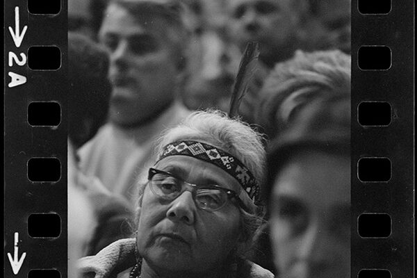 a black and white film photo of an indigenous woman in a crowd